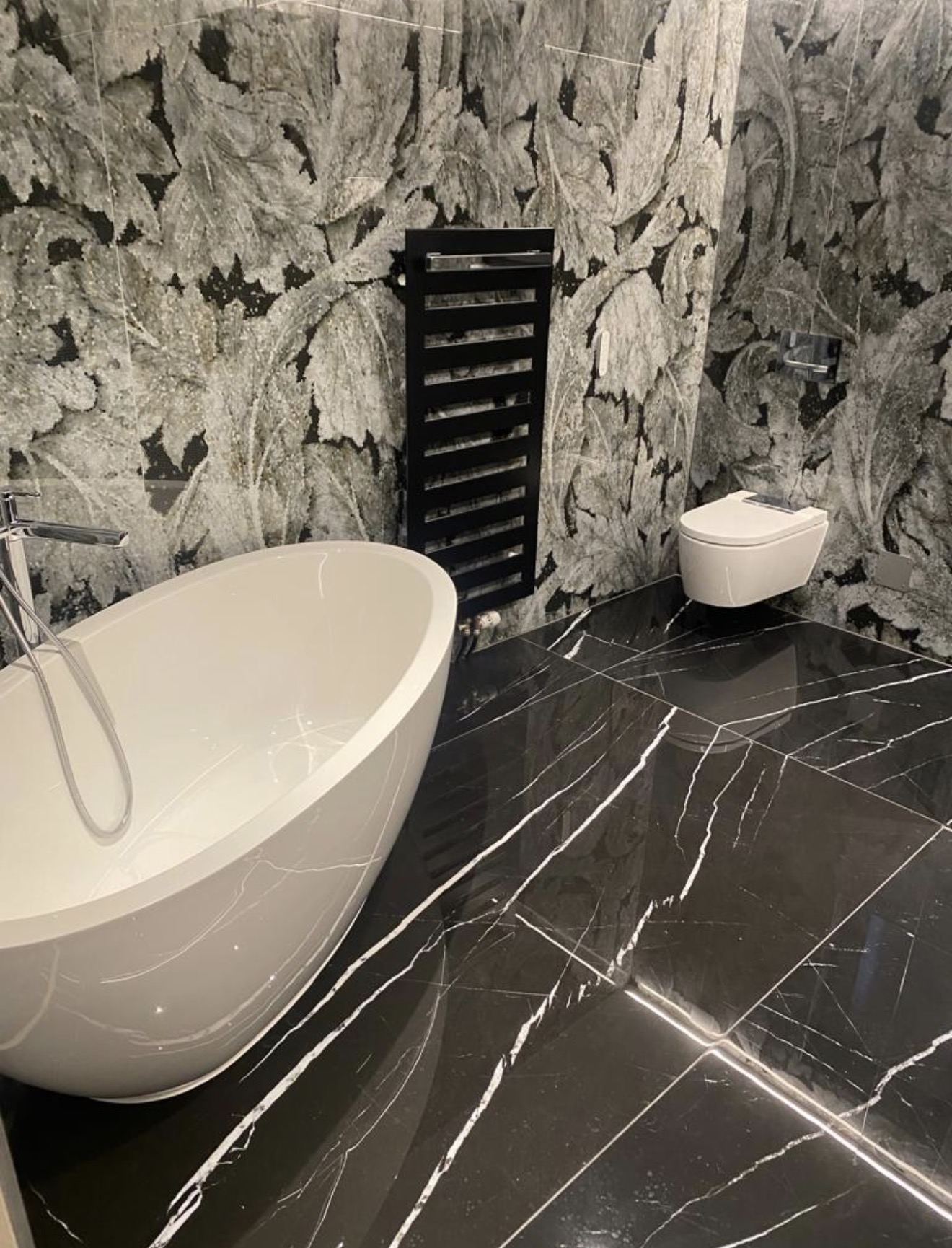 Baignoire îlot blanche, sol en marbre noir et mur en mosaïque végétale